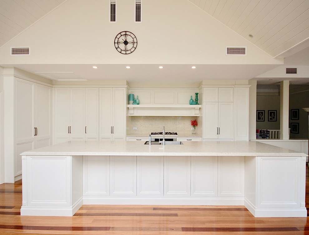 Design ideas for a large transitional galley eat-in kitchen in Sydney with a drop-in sink, recessed-panel cabinets, white cabinets, quartz benchtops, beige splashback, stone slab splashback, stainless steel appliances, medium hardwood floors and with island.