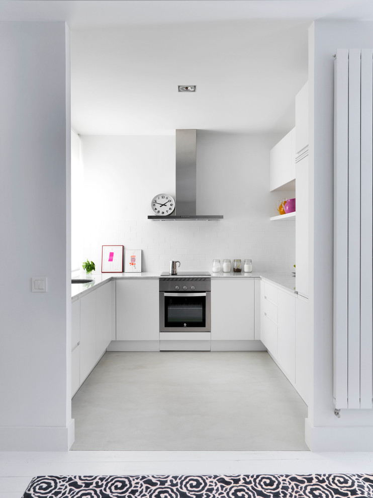 Design ideas for a mid-sized contemporary u-shaped kitchen in Madrid with flat-panel cabinets, white cabinets, white splashback, stainless steel appliances, no island, marble benchtops and ceramic splashback.