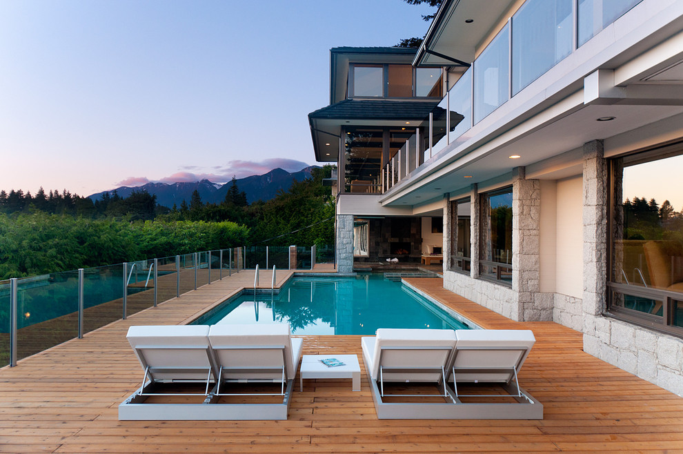 Design ideas for a large contemporary backyard custom-shaped pool in Vancouver with decking.