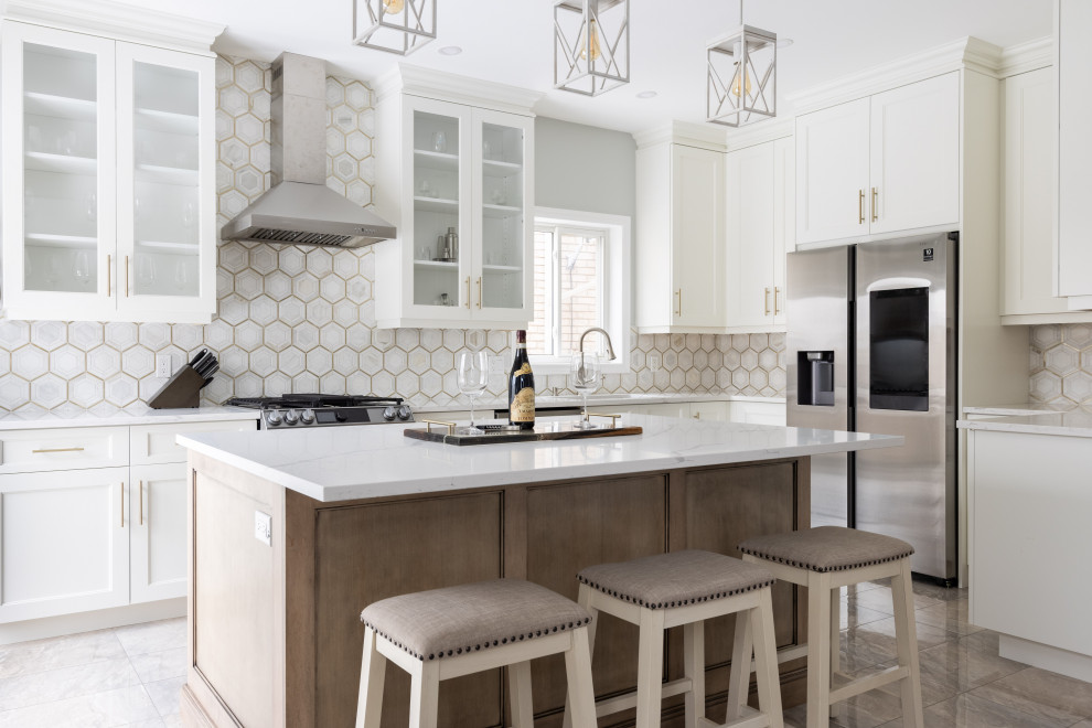 Inspiration for a transitional l-shaped kitchen remodel with glass-front cabinets, white cabinets, multicolored backsplash, stainless steel appliances, an island and white countertops