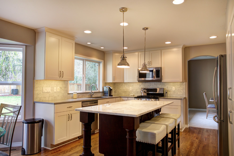 Mid-sized transitional l-shaped medium tone wood floor eat-in kitchen photo in Seattle with an undermount sink, recessed-panel cabinets, white cabinets, quartz countertops, white backsplash, stone tile backsplash, stainless steel appliances and an island