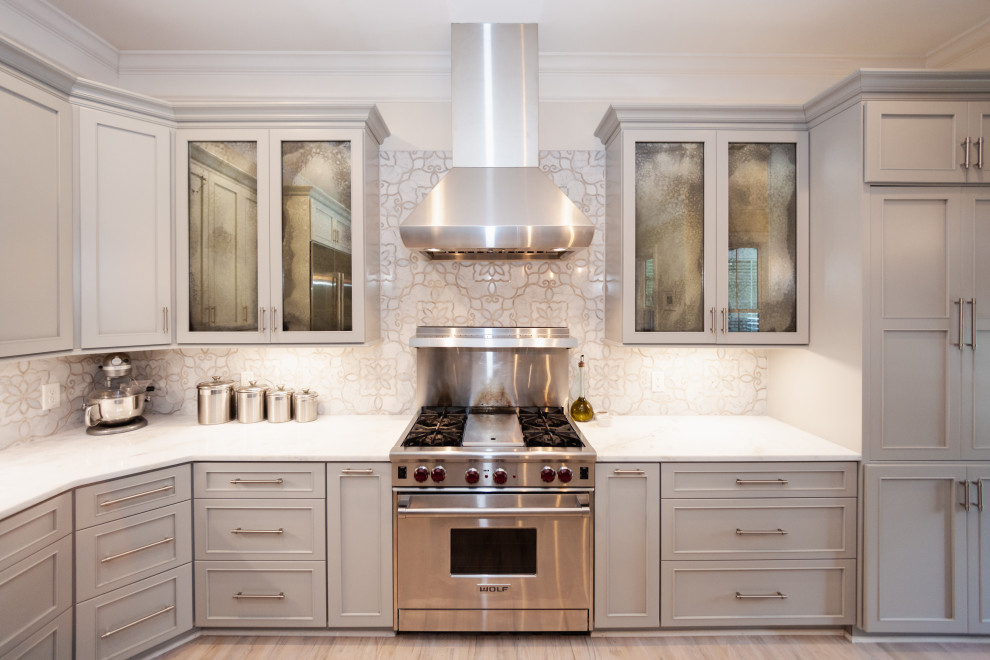 Example of a mid-sized transitional l-shaped light wood floor and beige floor open concept kitchen design in Charleston with an undermount sink, recessed-panel cabinets, gray cabinets, quartzite countertops, gray backsplash, marble backsplash, stainless steel appliances, an island and gray countertops