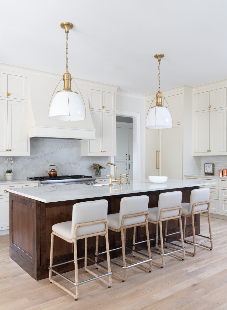 Mid-sized elegant u-shaped light wood floor open concept kitchen photo in Dallas with a farmhouse sink, beaded inset cabinets, white cabinets, quartzite countertops, stone slab backsplash, paneled appliances, an island and white countertops