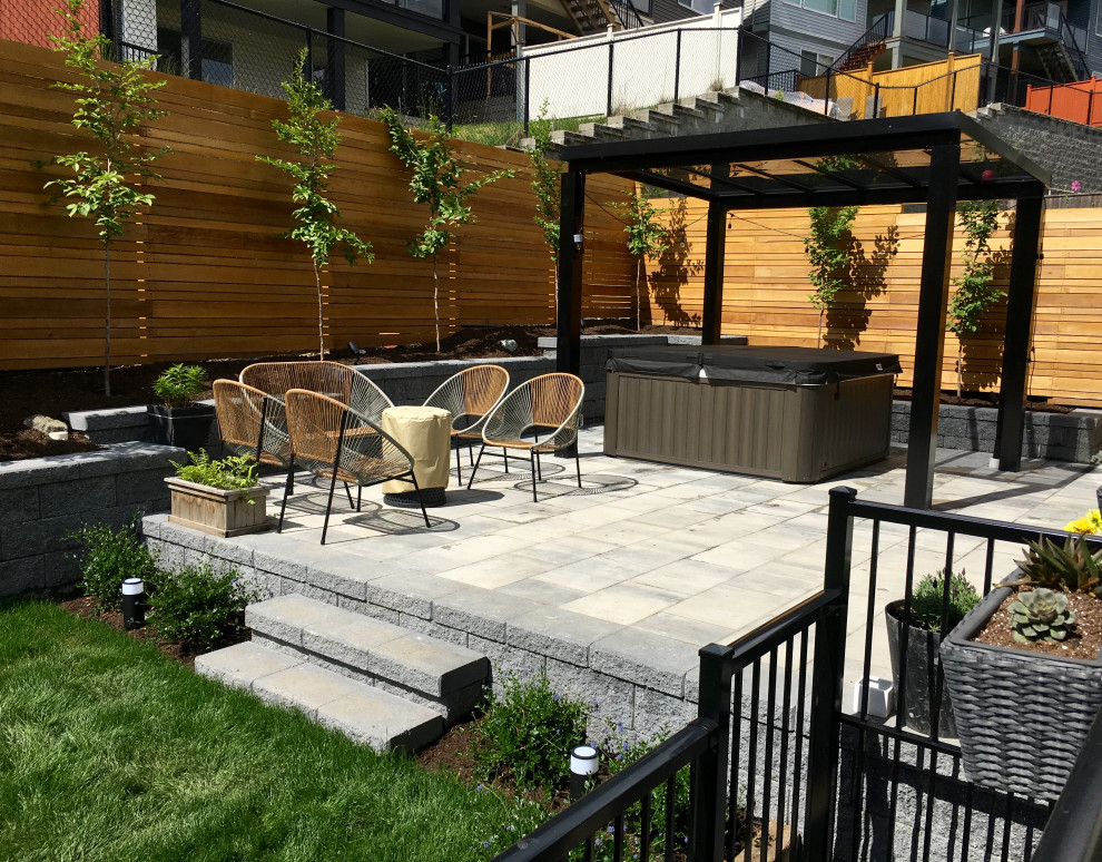 Foto di un giardino moderno esposto in pieno sole di medie dimensioni in primavera con pavimentazioni in cemento, recinzione in legno e un pendio, una collina o una riva