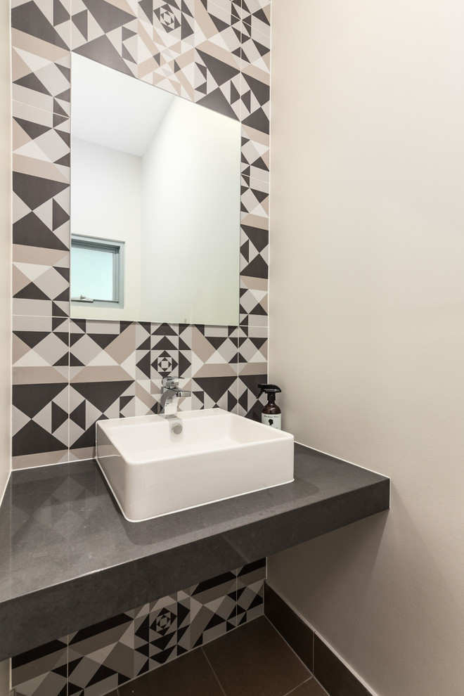 This is an example of a contemporary powder room in Sydney with black and white tile, grey walls, a vessel sink, grey floor and grey benchtops.