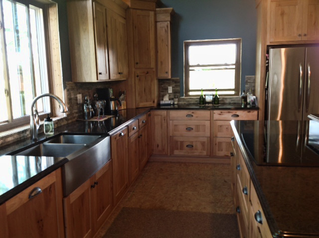 Mountain style u-shaped eat-in kitchen photo with a farmhouse sink, recessed-panel cabinets, light wood cabinets, granite countertops, multicolored backsplash, stainless steel appliances and an island