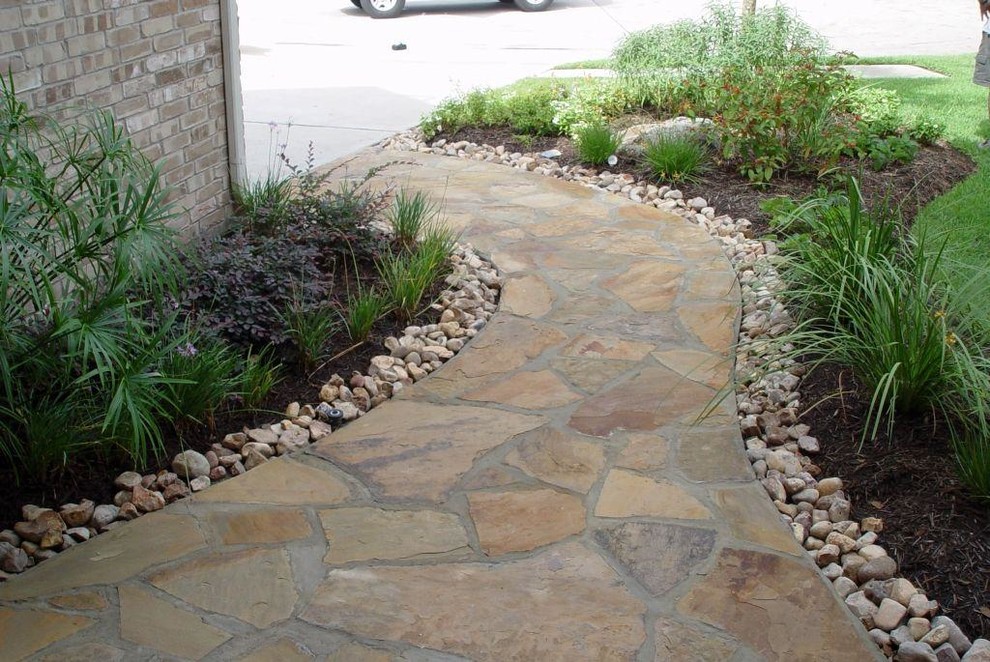 Inspiration for a mid-sized traditional side yard partial sun garden in Houston with natural stone pavers and a garden path.