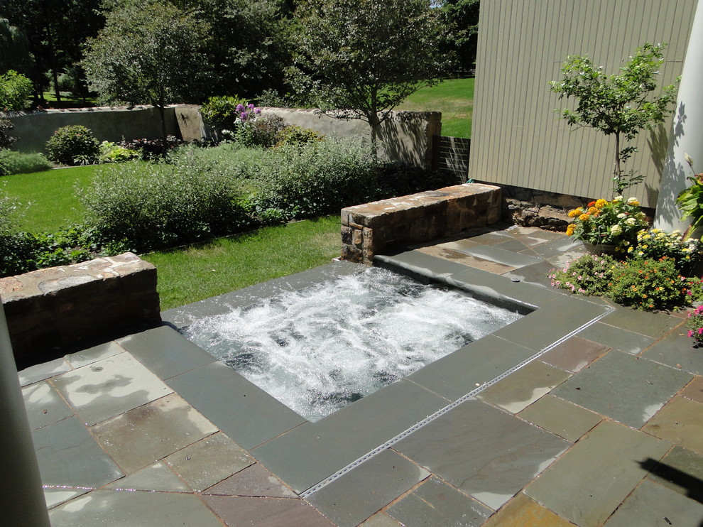 Inspiration for a small traditional courtyard rectangular infinity pool in Philadelphia with a hot tub and natural stone pavers.