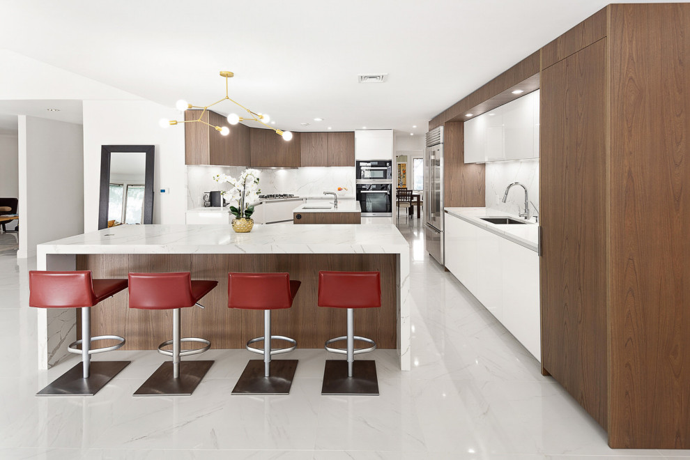 Inspiration for a large contemporary u-shaped eat-in kitchen in New York with an undermount sink, flat-panel cabinets, medium wood cabinets, quartz benchtops, white splashback, engineered quartz splashback, stainless steel appliances, porcelain floors, multiple islands, white floor and white benchtop.