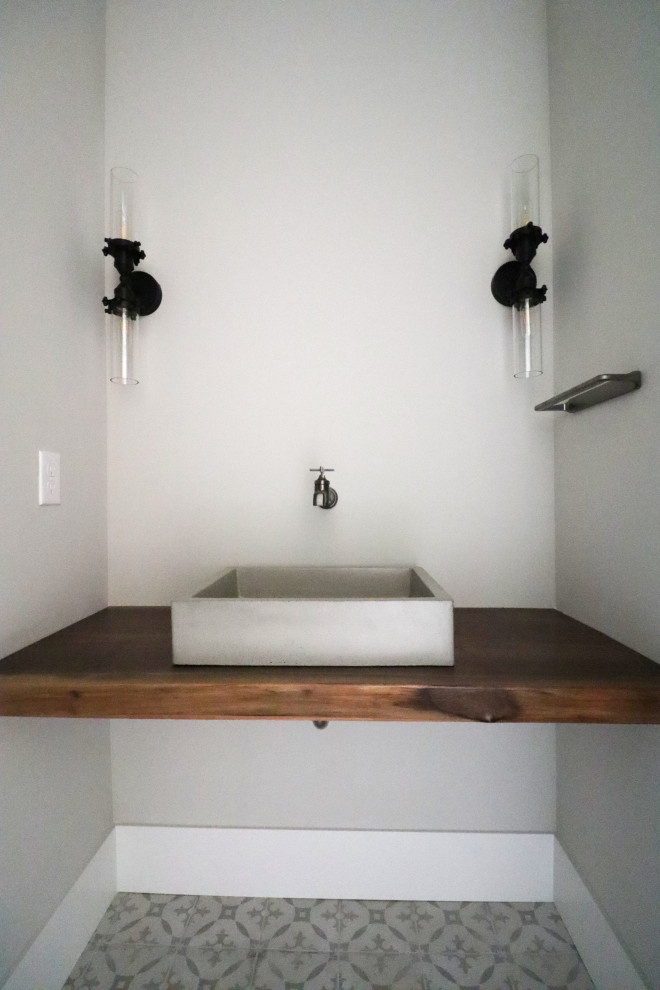 Industrial Gästetoilette mit Toilette mit Aufsatzspülkasten, Porzellan-Bodenfliesen, Aufsatzwaschbecken, Waschtisch aus Holz und schwebendem Waschtisch in Omaha