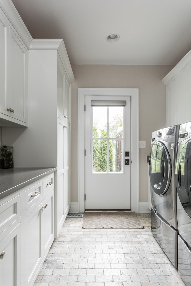 This is an example of a mid-sized traditional galley utility room in Indianapolis with an undermount sink, shaker cabinets, white cabinets, beige walls, brick floors, a side-by-side washer and dryer, multi-coloured floor and grey benchtop.
