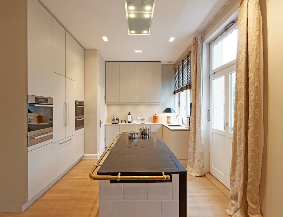 Design ideas for a mid-sized contemporary l-shaped open plan kitchen in Hamburg with white cabinets, white splashback, with island, an undermount sink, flat-panel cabinets, quartz benchtops, glass sheet splashback, stainless steel appliances, painted wood floors and grey floor.