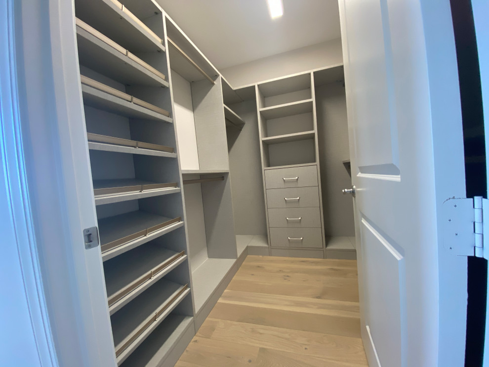 Aménagement d'une armoire encastrée contemporaine de taille moyenne et neutre avec un placard à porte plane, des portes de placard grises, parquet clair et un sol multicolore.
