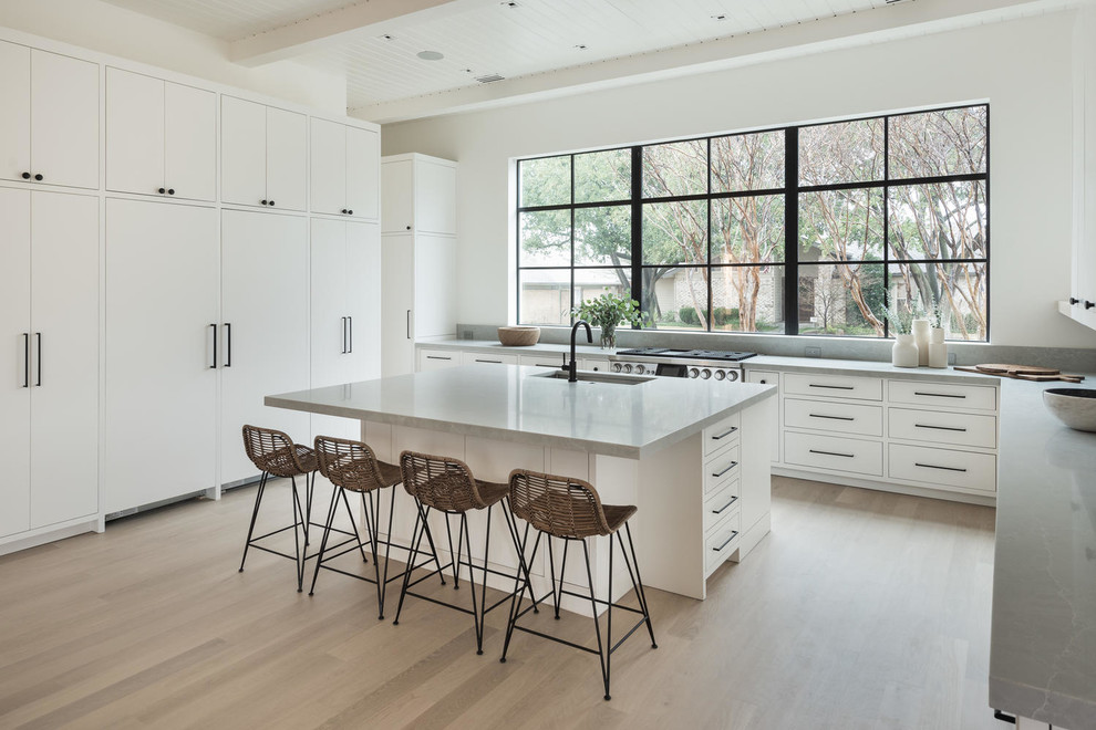 Design ideas for a large contemporary u-shaped open plan kitchen in Dallas with flat-panel cabinets, white cabinets, quartz benchtops, grey splashback, stone slab splashback, stainless steel appliances, light hardwood floors, with island, brown floor, grey benchtop and an undermount sink.