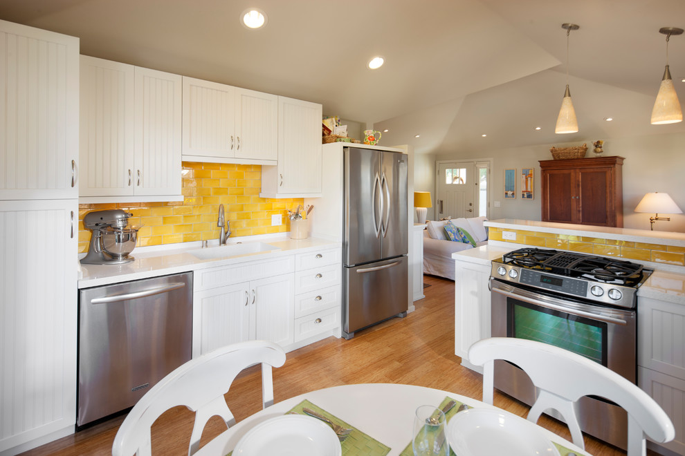 This is an example of a small galley separate kitchen in Santa Barbara with an integrated sink, beaded inset cabinets, turquoise cabinets, quartz benchtops, yellow splashback, ceramic splashback, stainless steel appliances, medium hardwood floors and no island.
