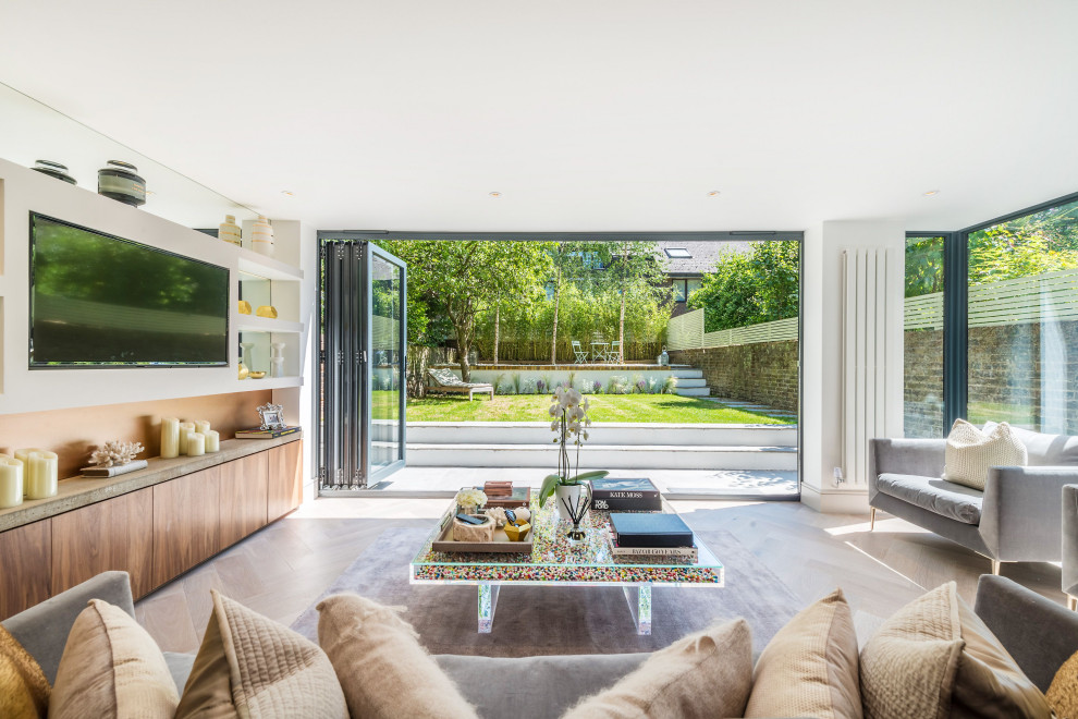 Foto di un grande soggiorno minimal aperto con pareti bianche, parquet chiaro, TV a parete e pavimento beige