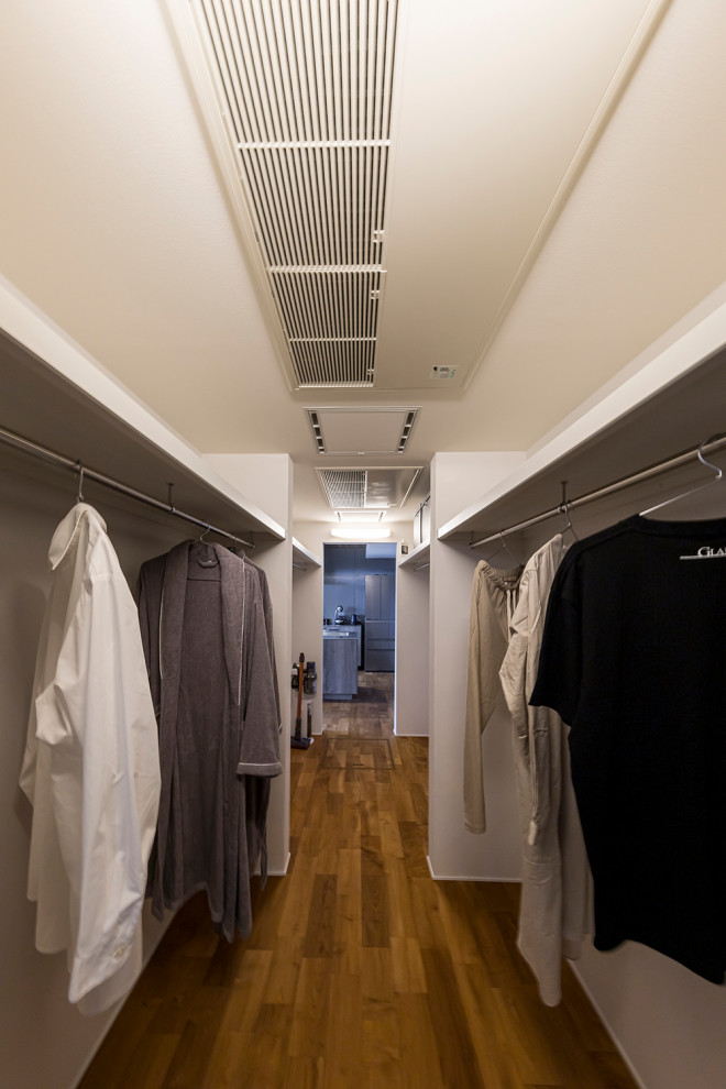 Ejemplo de armario vestidor de hombre retro con armarios abiertos, puertas de armario blancas, suelo de madera oscura, suelo marrón y papel pintado
