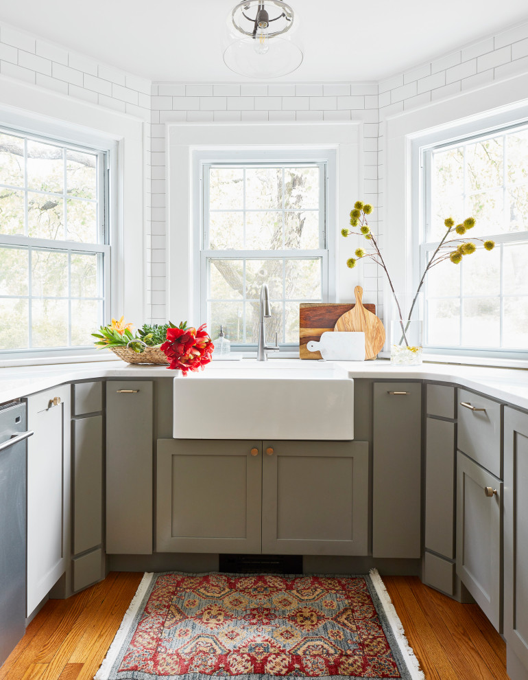 Example of a mid-sized transitional galley medium tone wood floor and brown floor eat-in kitchen design with a farmhouse sink, shaker cabinets, gray cabinets, quartz countertops, white backsplash, subway tile backsplash, stainless steel appliances, no island and white countertops