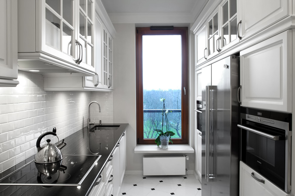 This is an example of a traditional galley eat-in kitchen in Other with an undermount sink, white cabinets, granite benchtops, white splashback, porcelain splashback and stainless steel appliances.