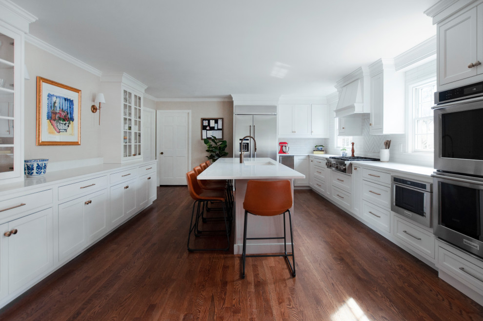 Inspiration for a transitional u-shaped kitchen in Nashville with an undermount sink, shaker cabinets, white cabinets, white splashback, stainless steel appliances, dark hardwood floors, with island, brown floor and white benchtop.