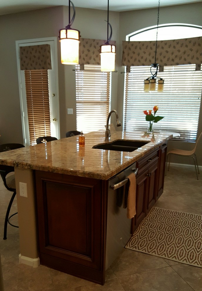Example of a transitional single-wall eat-in kitchen design in Phoenix with an undermount sink, dark wood cabinets, granite countertops, brown backsplash, glass tile backsplash, stainless steel appliances and an island