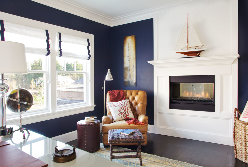 Photo of a large beach style home office in Portland with blue walls, dark hardwood floors, a two-sided fireplace, a wood fireplace surround and a freestanding desk.