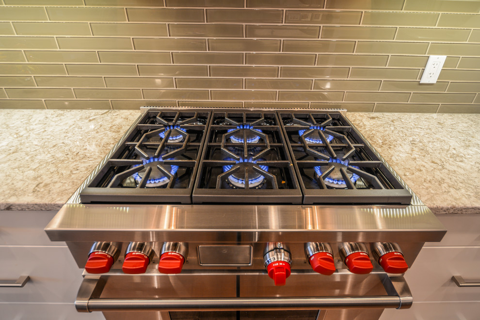 Large transitional l-shaped medium tone wood floor open concept kitchen photo in Calgary with an undermount sink, shaker cabinets, white cabinets, granite countertops, gray backsplash, porcelain backsplash, stainless steel appliances and an island