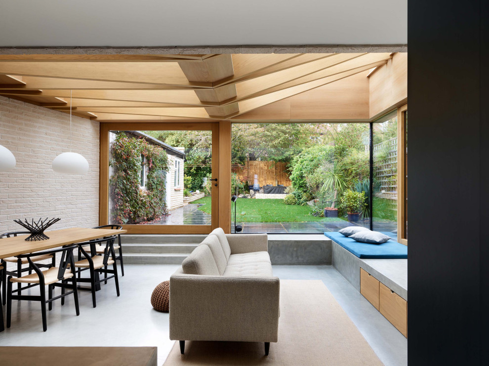 Medium sized scandinavian open plan living room in London with a wood burning stove, a freestanding tv, exposed beams, brick walls and feature lighting.