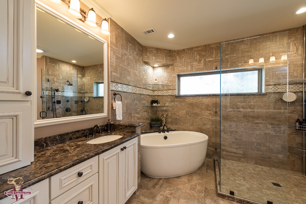 Design ideas for a mid-sized modern master bathroom in Dallas with raised-panel cabinets, distressed cabinets, a freestanding tub, a corner shower, a one-piece toilet, beige tile, stone tile, beige walls, ceramic floors, an undermount sink and granite benchtops.
