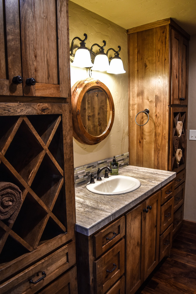 This is an example of a small country 3/4 bathroom in Dallas with shaker cabinets, medium wood cabinets, gray tile, green tile, white tile, matchstick tile, beige walls, dark hardwood floors, a drop-in sink, granite benchtops and brown floor.