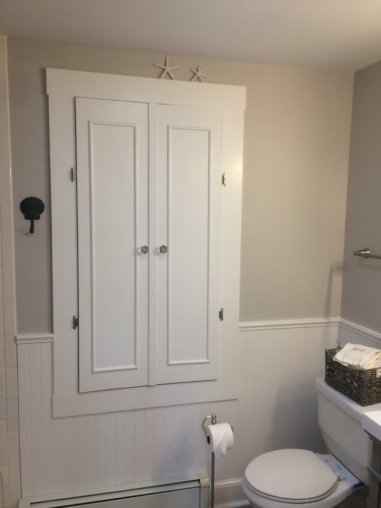 Photo of a small transitional powder room in Boston with recessed-panel cabinets, grey cabinets, a two-piece toilet, grey walls, porcelain floors, an integrated sink, solid surface benchtops and grey floor.
