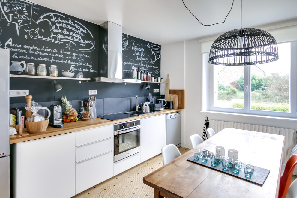 This is an example of a large scandinavian single-wall eat-in kitchen in Brest with a single-bowl sink, flat-panel cabinets, white cabinets, wood benchtops, black splashback, stainless steel appliances, ceramic floors, brown benchtop, no island, beige floor and stone slab splashback.