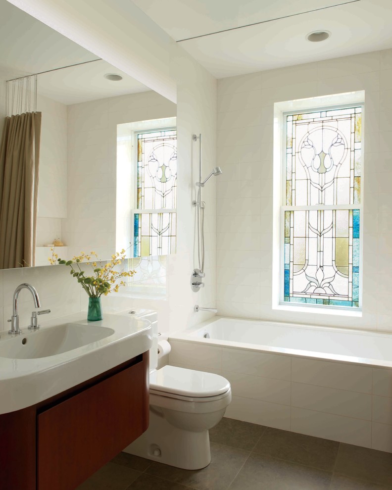 Inspiration for a contemporary bathroom in New York with a wall-mount sink, a drop-in tub and white walls.