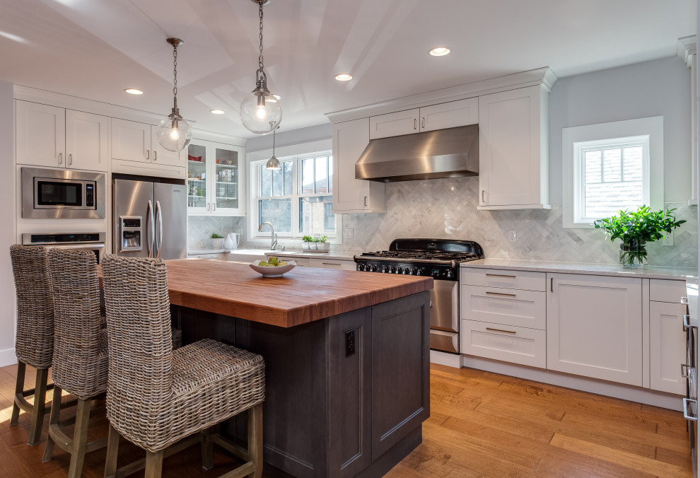 Design ideas for a large arts and crafts galley open plan kitchen in Denver with a farmhouse sink, shaker cabinets, white cabinets, granite benchtops, white splashback, glass tile splashback, stainless steel appliances, medium hardwood floors, with island and white benchtop.