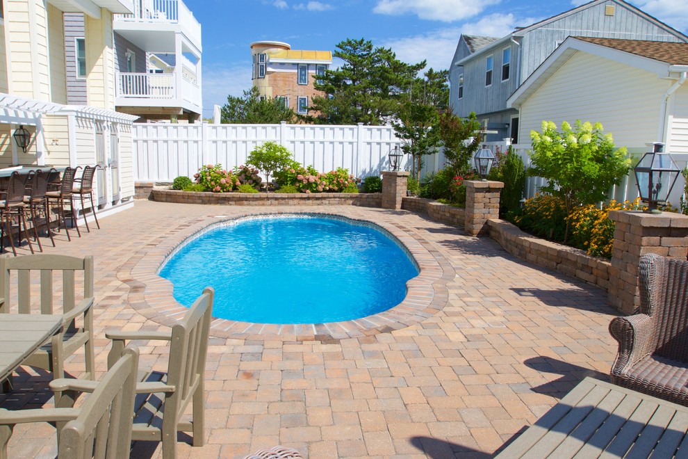 Large traditional backyard custom-shaped natural pool in New York with natural stone pavers.