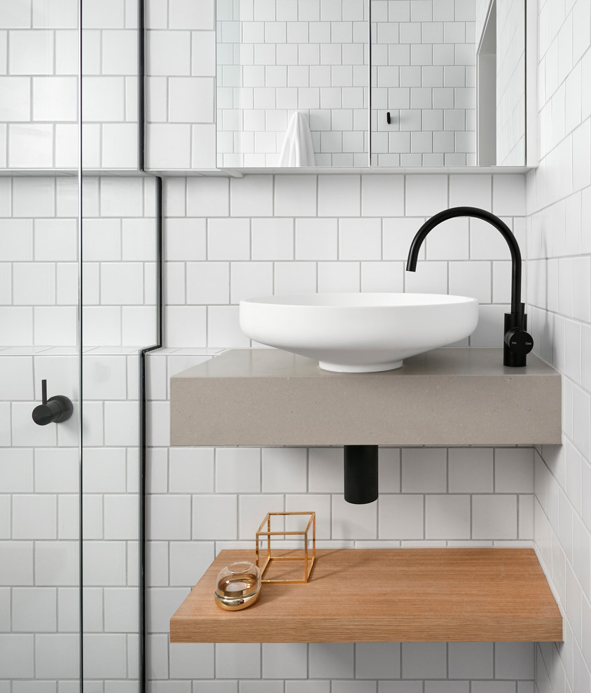 This is an example of a small scandinavian bathroom in Melbourne with open cabinets, light wood cabinets, a curbless shower, white tile, subway tile, white walls, mosaic tile floors, a wall-mount sink, solid surface benchtops and a hinged shower door.