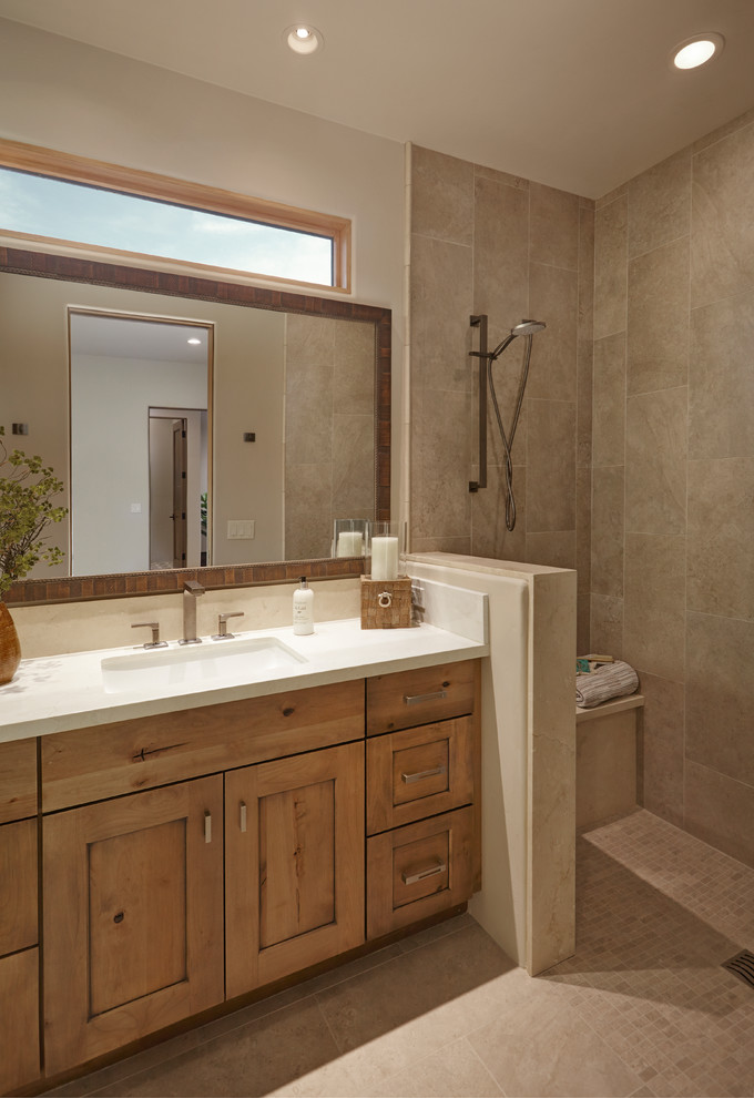 Design ideas for a large bathroom in Phoenix with recessed-panel cabinets, brown cabinets, an undermount tub, an alcove shower, a one-piece toilet, beige tile, porcelain tile, beige walls, porcelain floors, an undermount sink, limestone benchtops, beige floor, an open shower and beige benchtops.