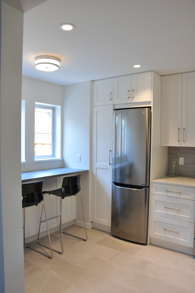 Example of a small transitional u-shaped vinyl floor and beige floor eat-in kitchen design in Vancouver with a single-bowl sink, shaker cabinets, white cabinets, quartz countertops, gray backsplash, ceramic backsplash, stainless steel appliances, no island and gray countertops