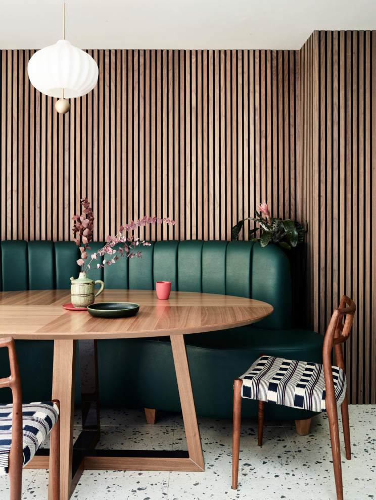 Contemporary dining room in London with banquette seating, multi-coloured floors and wood walls.