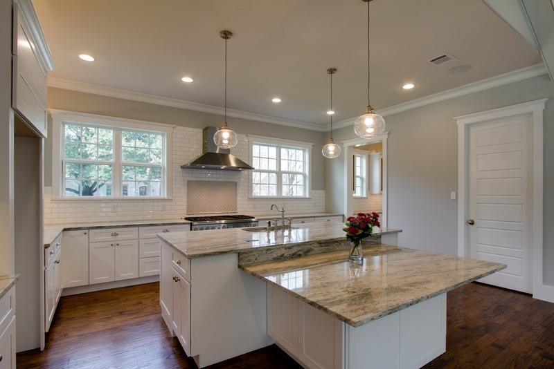 Large transitional u-shaped medium tone wood floor open concept kitchen photo in Dallas with a drop-in sink, flat-panel cabinets, white cabinets, granite countertops, white backsplash, subway tile backsplash, stainless steel appliances and an island