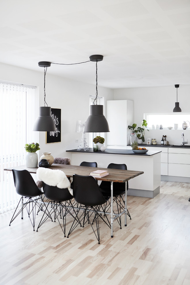 Scandinavian dining room in Wiltshire with white walls, light hardwood floors and no fireplace.