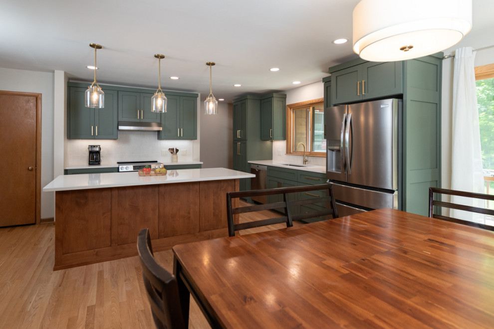 Transitional light wood floor kitchen photo with shaker cabinets, green cabinets, quartz countertops, white backsplash, ceramic backsplash and an island