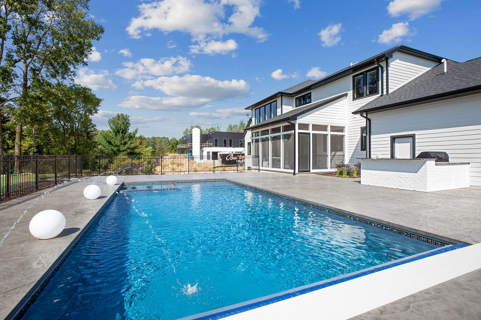 Large transitional backyard concrete paver and rectangular pool landscaping photo