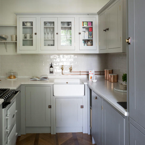 Photo of a small u-shaped separate kitchen in London with a single-bowl sink, glass-front cabinets, grey cabinets, granite benchtops, white splashback, ceramic splashback, white appliances, medium hardwood floors and no island.