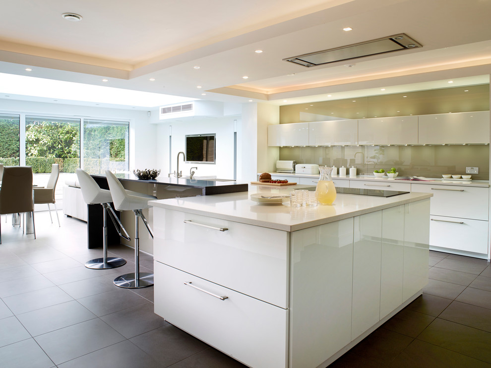 Inspiration for a contemporary l-shaped open plan kitchen in Manchester with flat-panel cabinets, white cabinets, beige splashback, glass sheet splashback and with island.