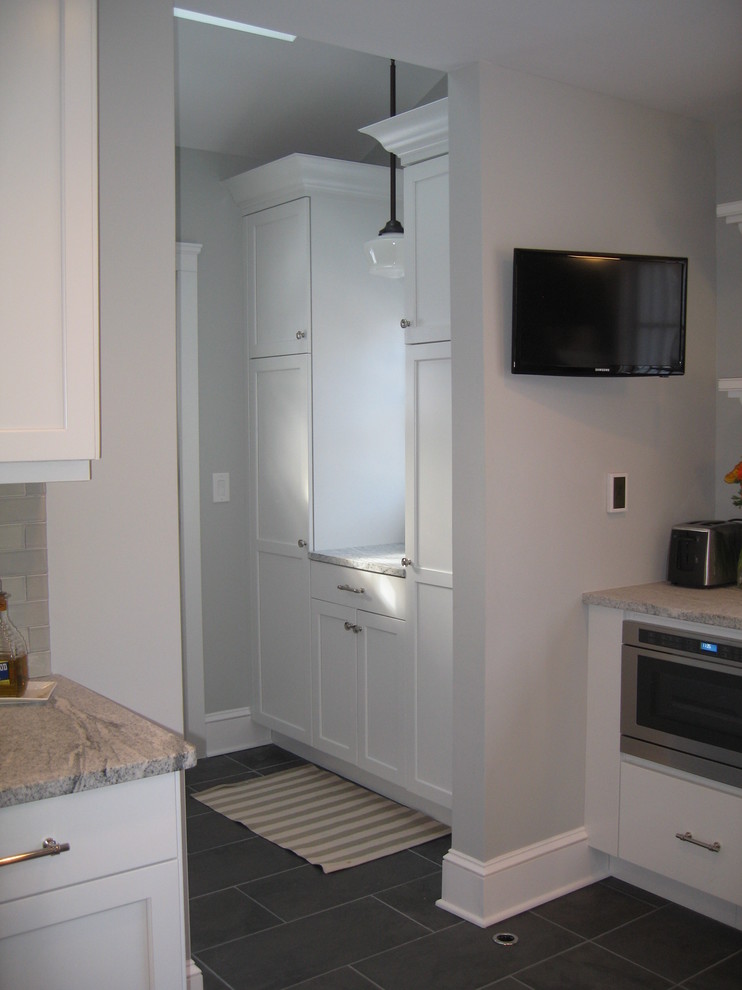 Inspiration for a transitional slate floor eat-in kitchen remodel in New York with a farmhouse sink, recessed-panel cabinets, white cabinets and stainless steel appliances