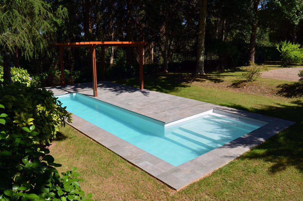 Mid-sized country backyard l-shaped lap pool in Other with a pool house and tile.