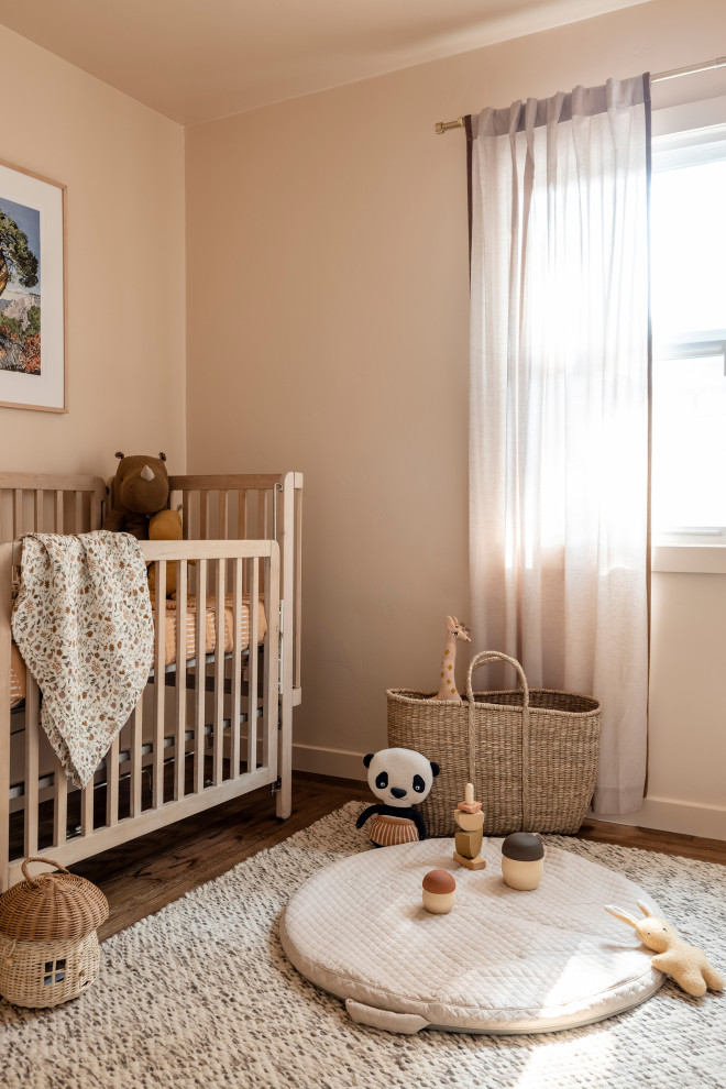 Esempio di una piccola cameretta per bambini da 1 a 3 anni con pareti rosa e pavimento in legno massello medio