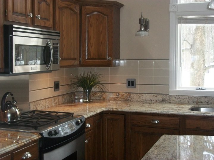 Example of a transitional kitchen design with a double-bowl sink, medium tone wood cabinets, beige backsplash, stainless steel appliances and an island
