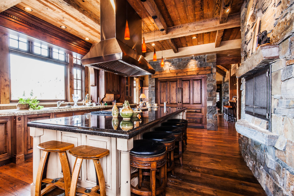 Eat-in kitchen - large rustic single-wall dark wood floor eat-in kitchen idea with an undermount sink, raised-panel cabinets, dark wood cabinets, granite countertops, stainless steel appliances and an island